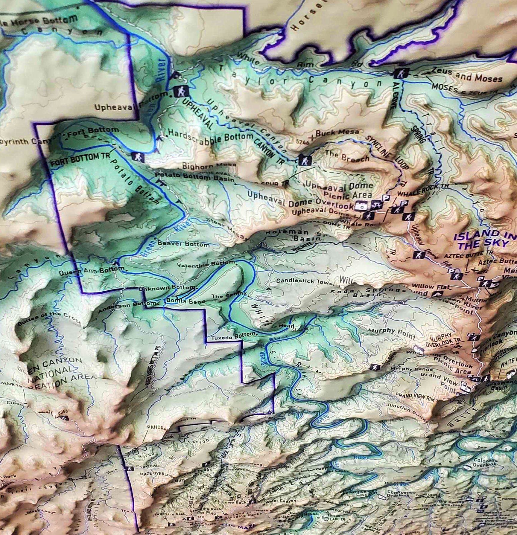 Three dimensional (3D) raised relief map of Canyonlands National Park, Utah, showcasing The Needles, The Maze, and Mesa Arch in stunning detail. The map highlights canyons, mesas, buttes, and rivers that shape this dramatic landscape.